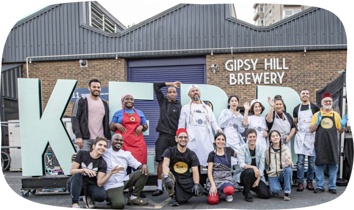 People wearing aprons pose happily in front of large letters spelling 